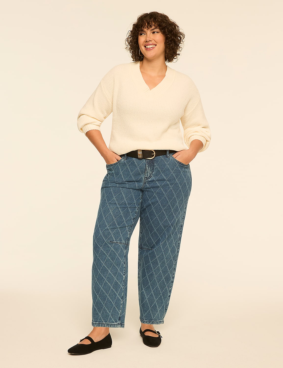 A smiling woman wearing a cream-colored sweater and patterned blue jeans stands against a plain, light-colored background. Product Image 3