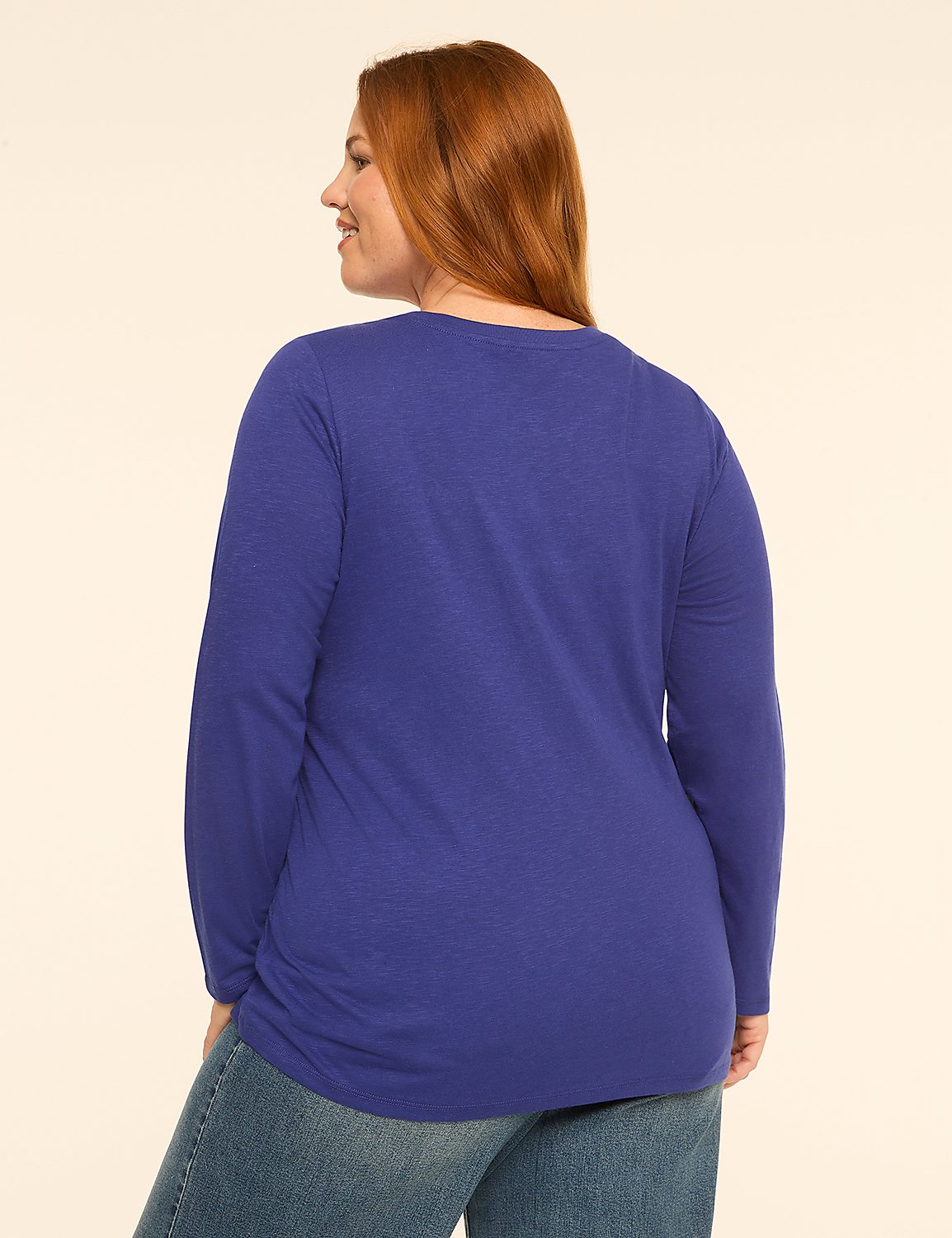 A woman with red hair wearing a blue long-sleeved shirt and jeans stands against a plain, light-colored background. Product Image 2