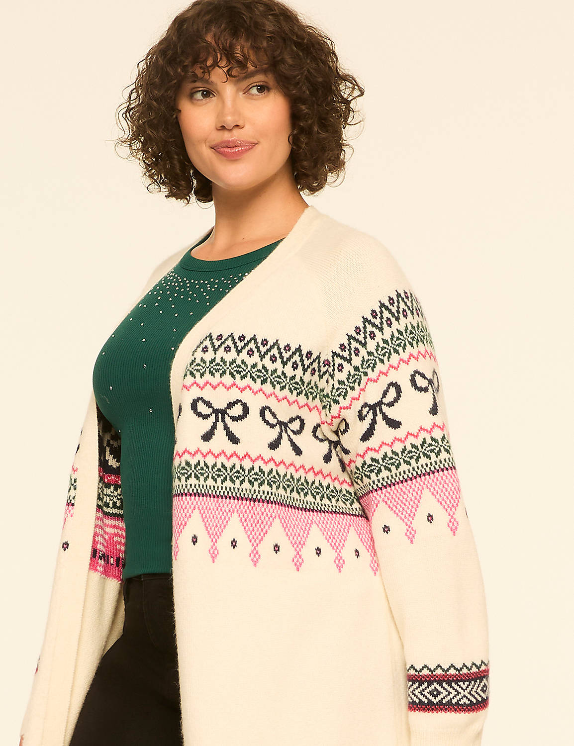 A woman with curly hair wearing a green top and a patterned white cardigan stands against a plain white background. Product Image 4