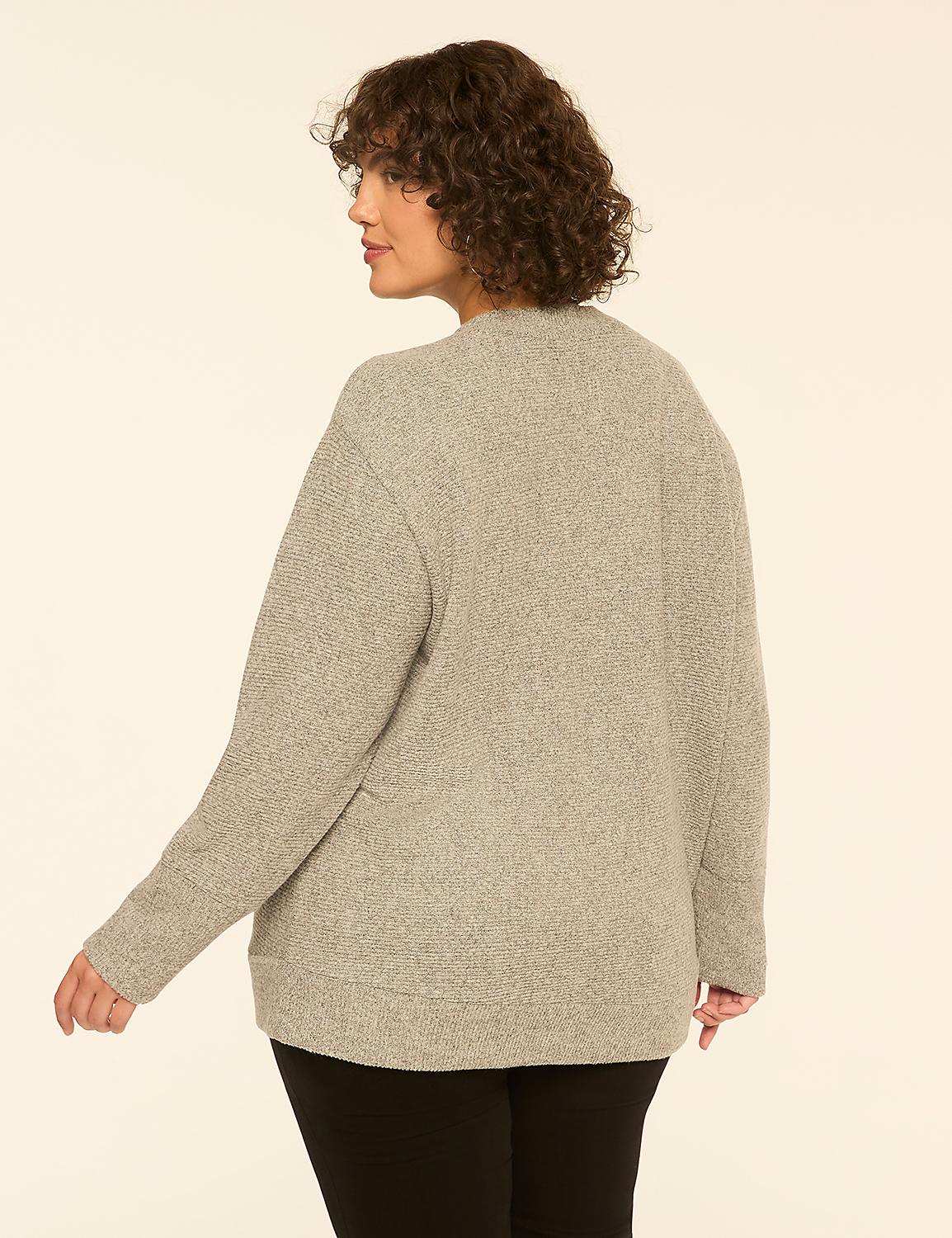 A woman with curly brown hair wearing a grey textured cardigan and black pants stands against a plain off-white background. Product Image 2