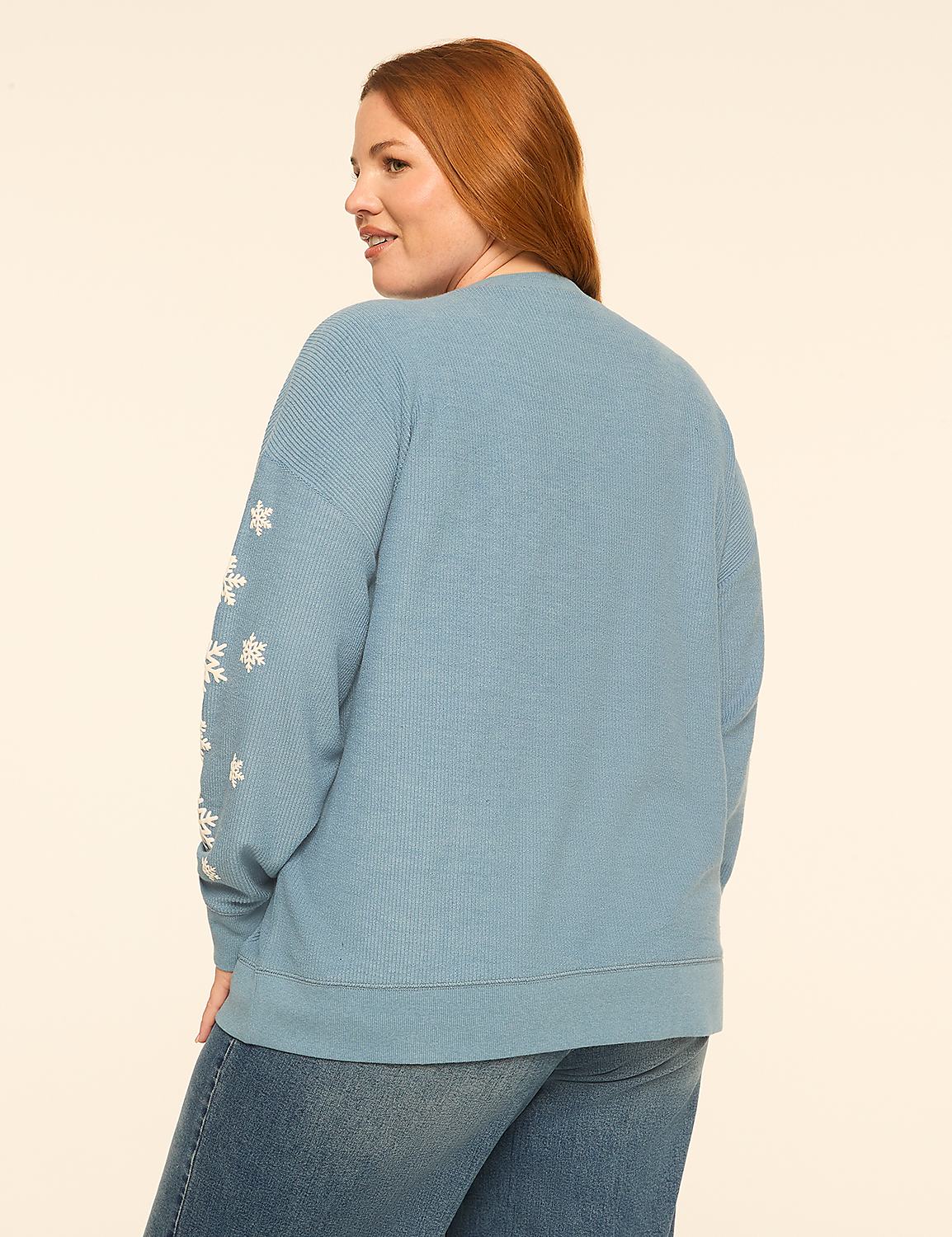 A woman with red hair wearing a blue snowflake-patterned sweater and jeans stands against a plain white background. Product Image 2
