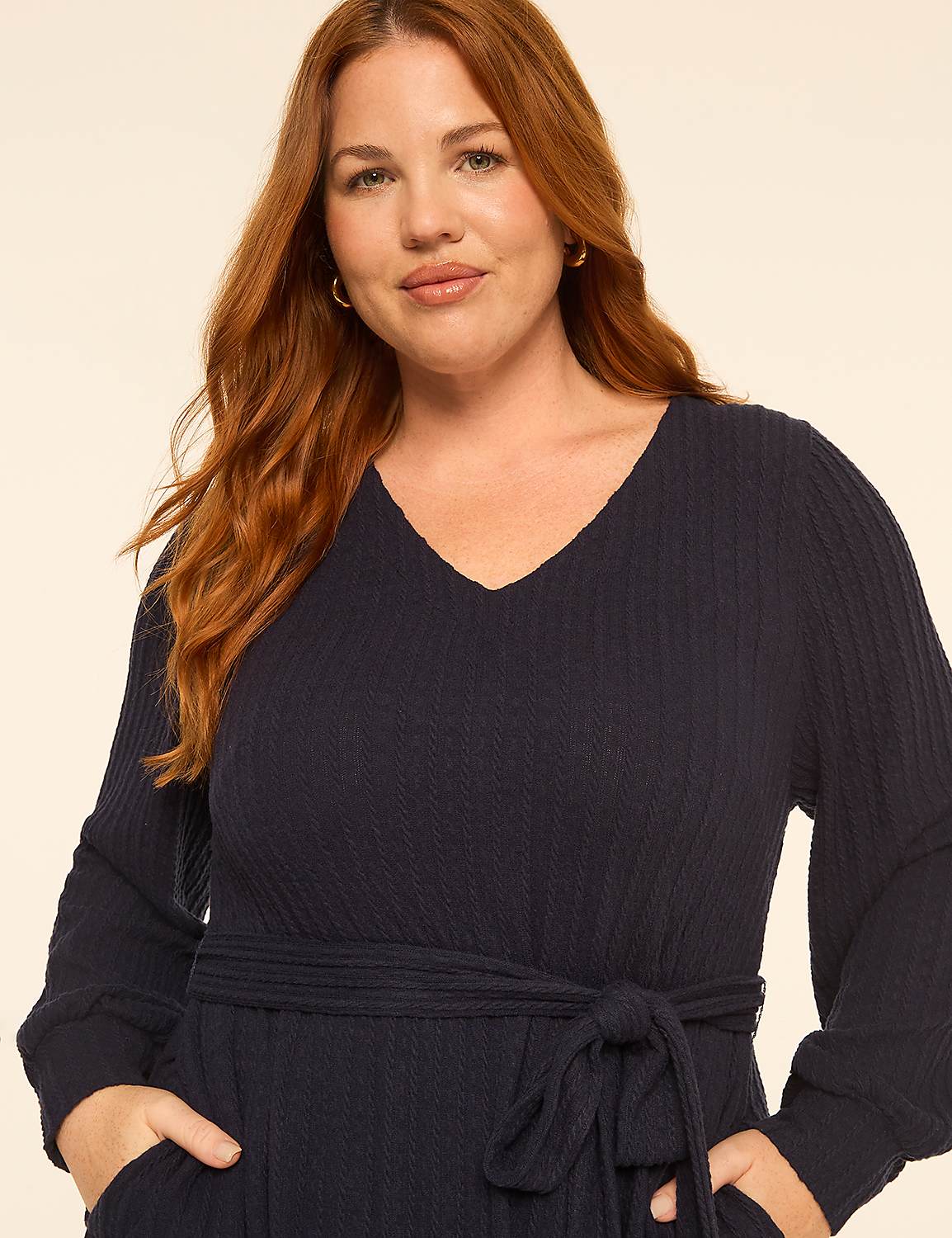 A woman with long red hair wearing a navy blue v-neck dress stands against a plain, light-colored background. Product Image 3