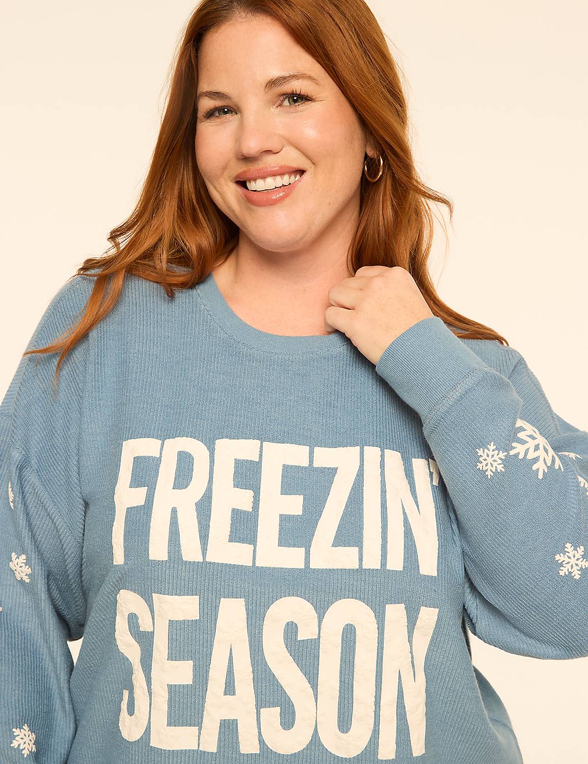 A smiling woman with red hair wears a blue "FREEZIN' SEASON" sweater against a plain, light-colored background. Product Image 4
