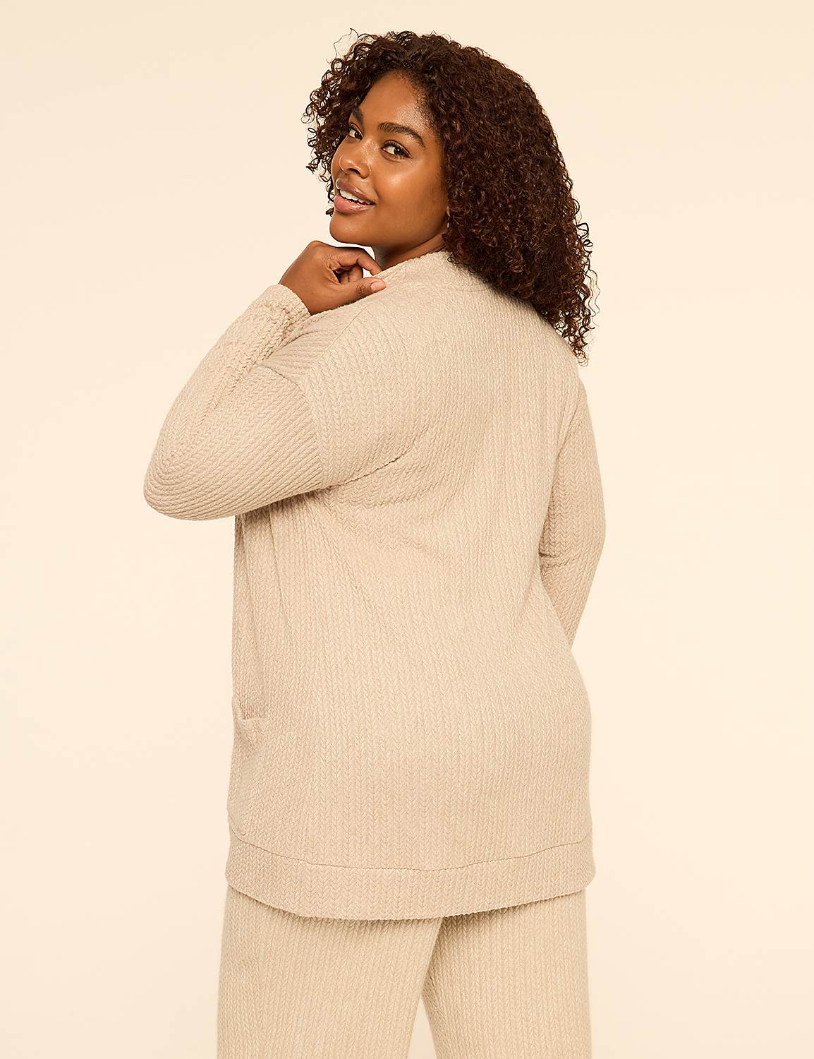 A woman with curly hair wearing a beige ribbed lounge set poses against a plain, light-colored background. Product Image 2