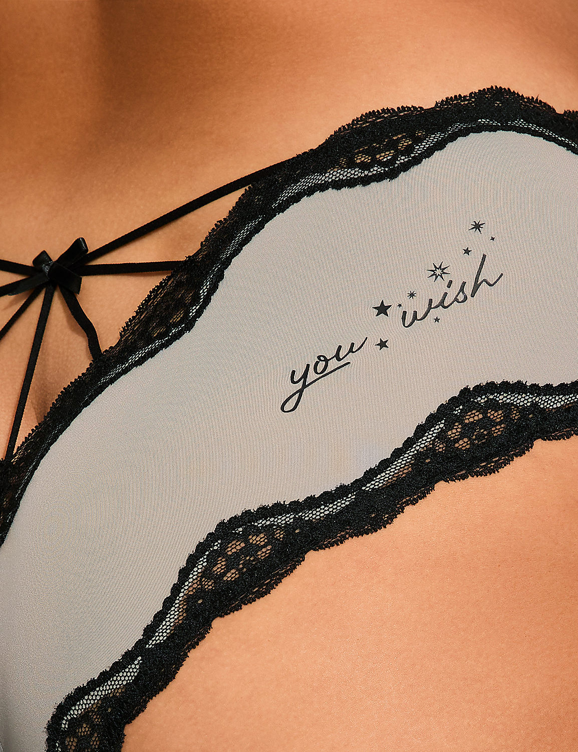 Grey lingerie with black lace trim and the words "you wish" is worn against a background of smooth skin. Product Image 4