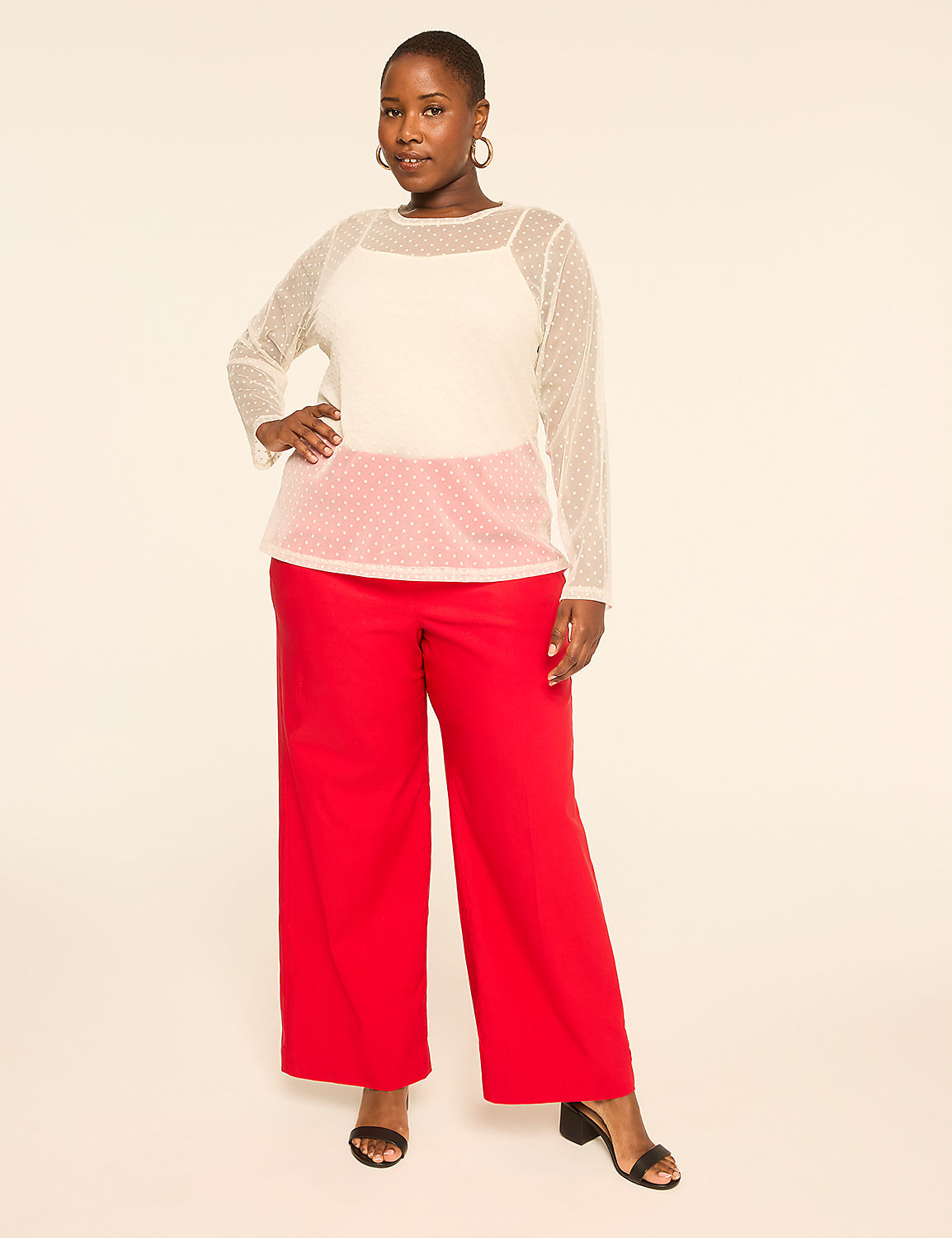 A woman wearing a white polka-dot blouse and wide-leg red trousers stands against a plain, light-colored background. Product Image 3