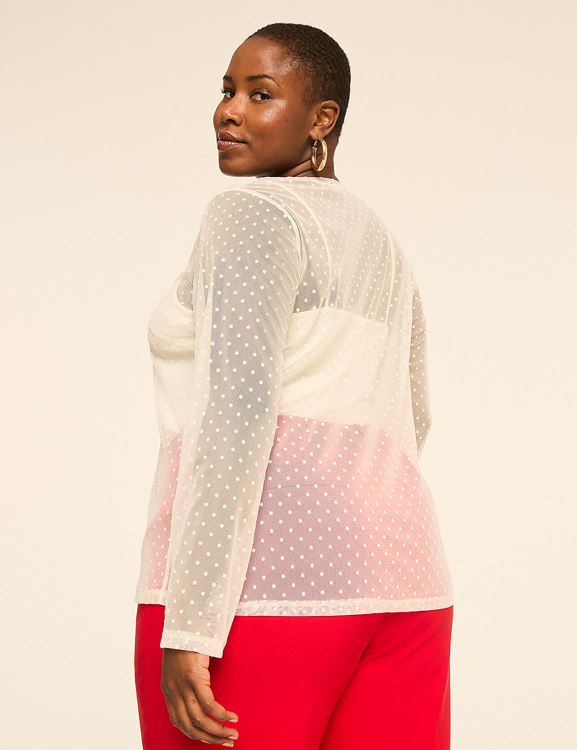 A woman wearing a sheer white polka-dot top and red pants stands against a plain, light-colored background. Product Image 2