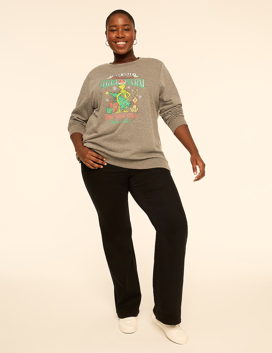 A smiling woman wearing a grey graphic long-sleeve shirt and black pants stands against a plain white background. Product Image 3
