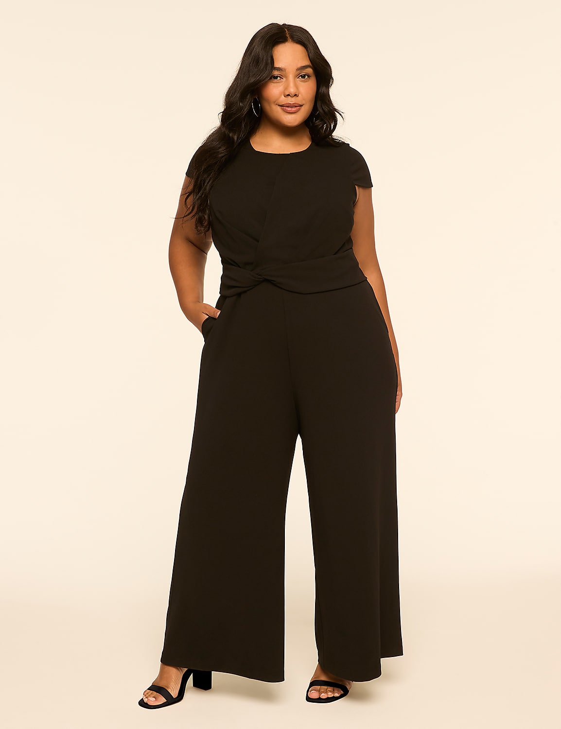 A woman in a black jumpsuit stands against a plain, light-colored background. Product Image 1