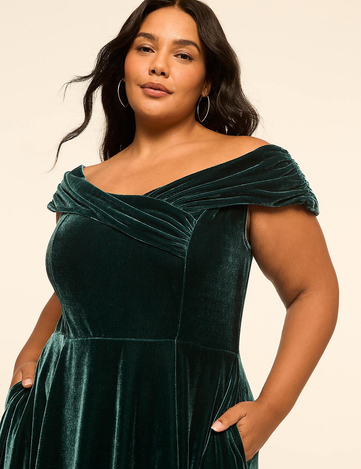 A woman in a green velvet dress with her hands in her pockets stands against a plain, light-colored background. Product Image 3