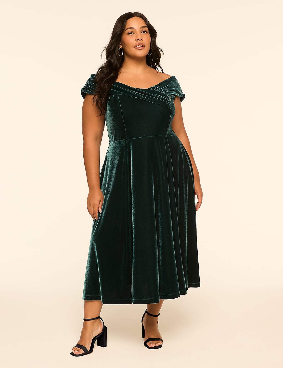 A plus-size woman in a dark green velvet off-the-shoulder dress stands against a plain, light-colored background. Product Image 1
