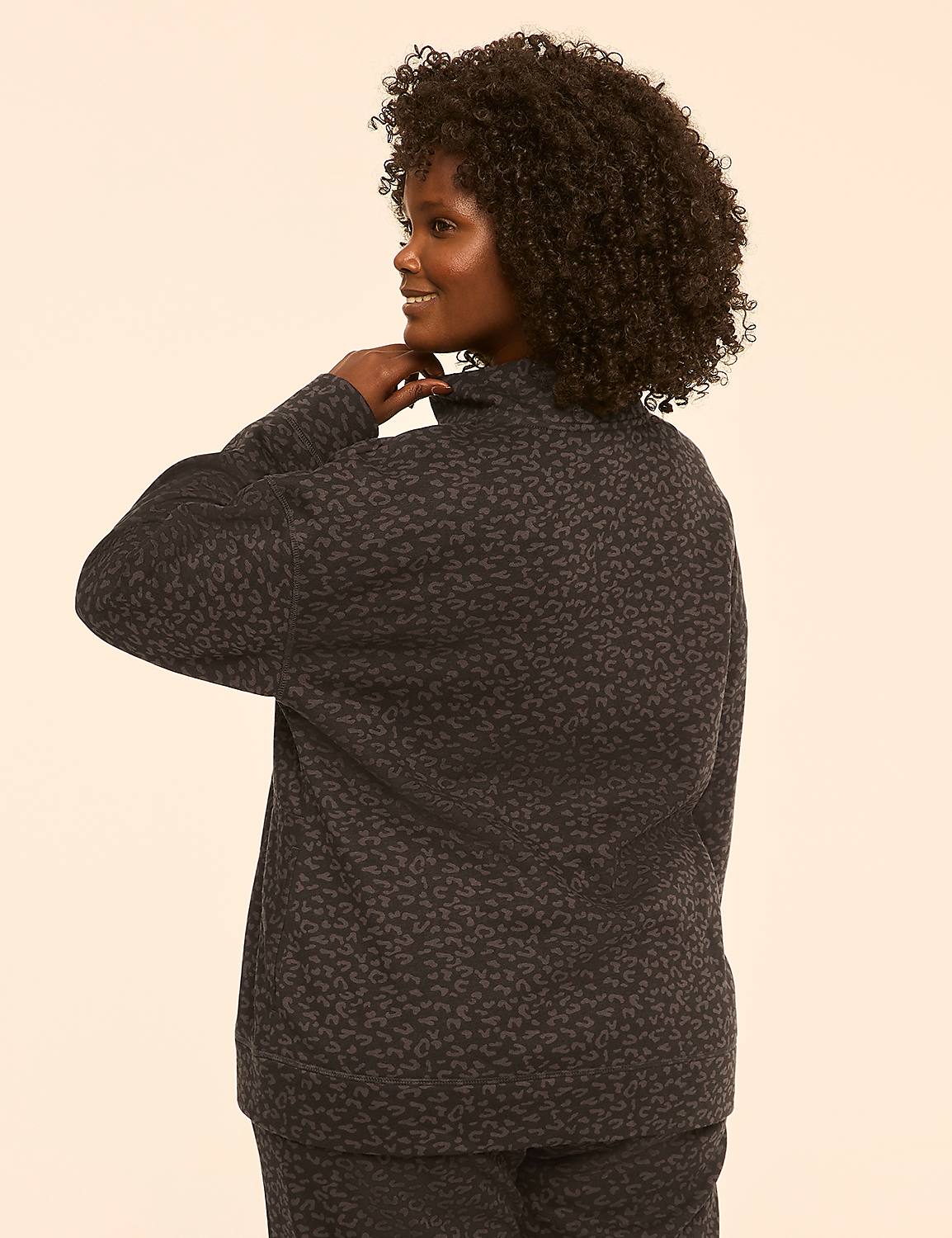 A woman with curly dark hair, wearing a patterned dark top and pants, is shown from the back with her hand on her neck against a plain, light-colored background. Product Image 2