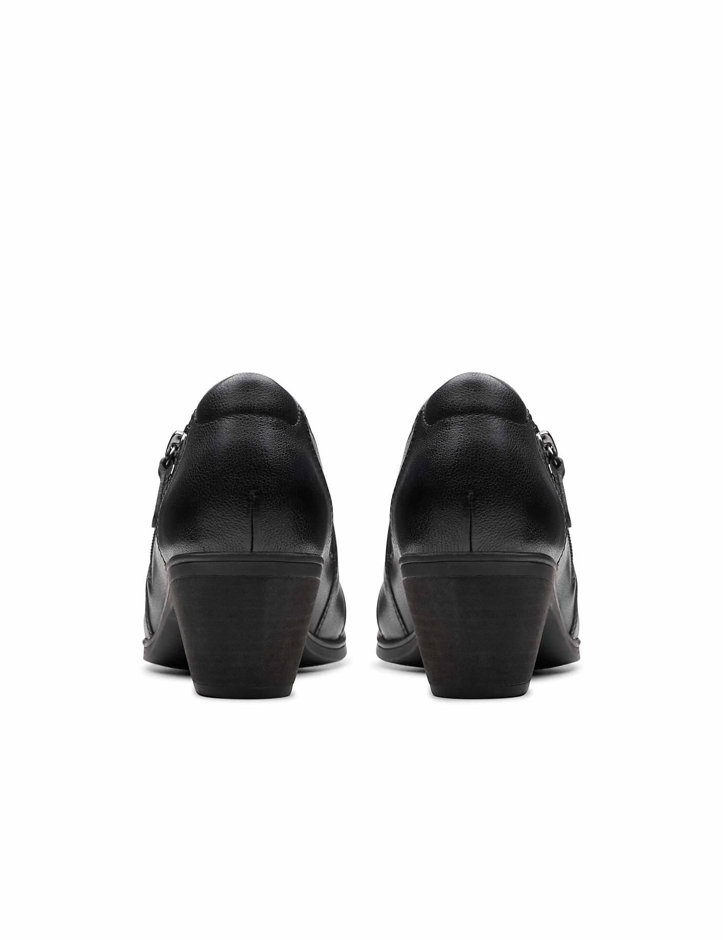A pair of black leather heeled shoes are positioned in the foreground against a plain white background. Product Image 2