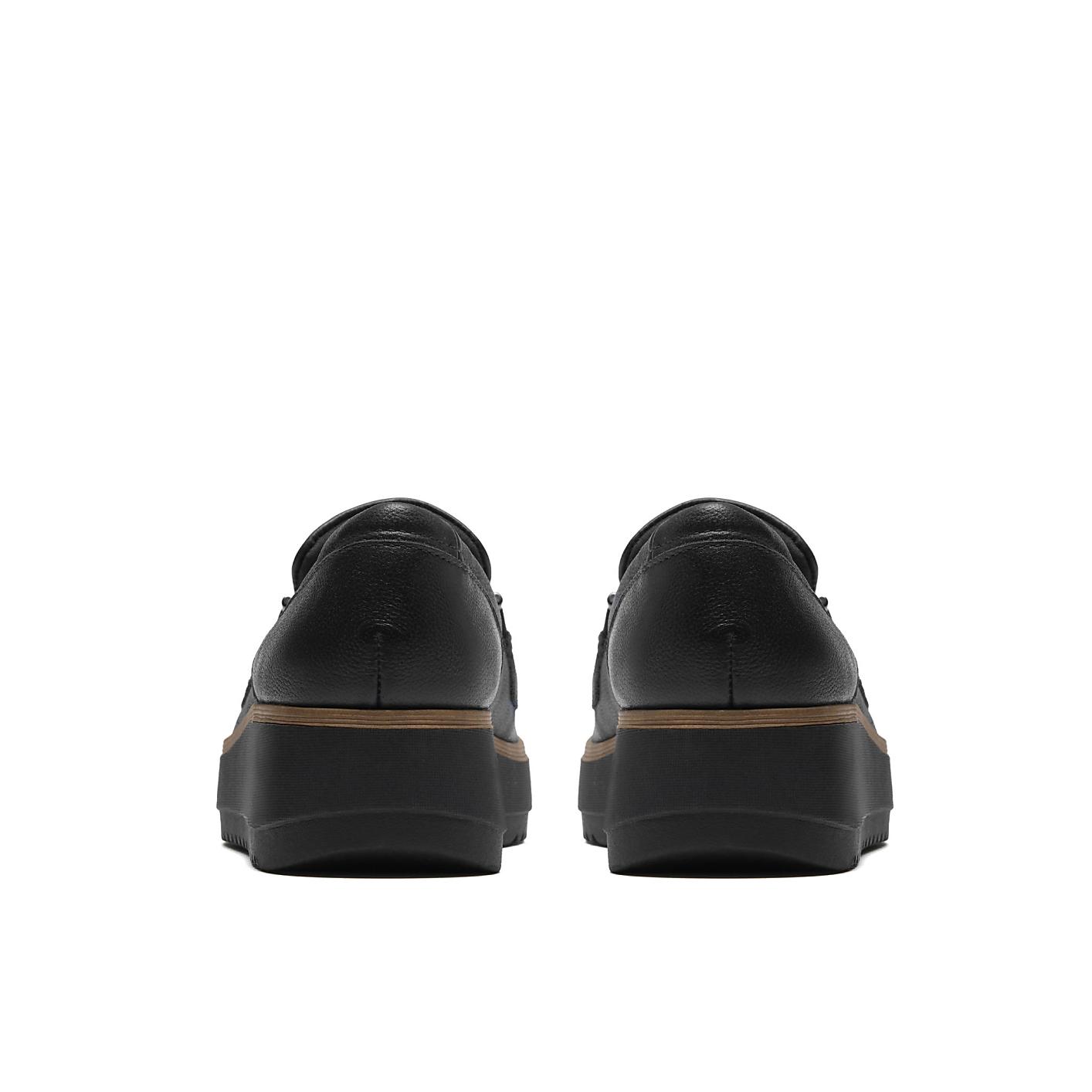 A pair of black leather platform shoes is positioned in the foreground against a plain white background. Product Image 2