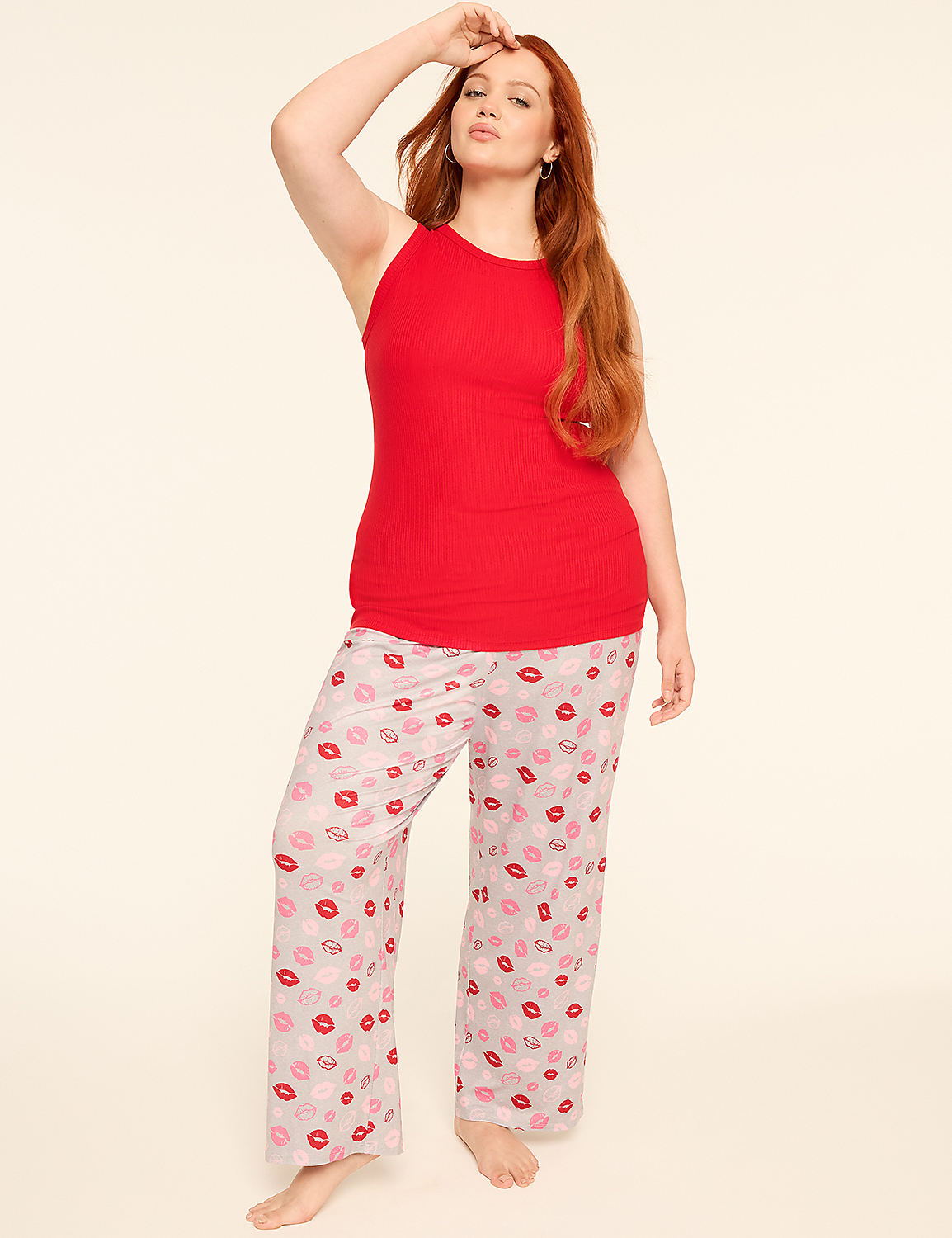 A red-haired woman wearing a red tank top and lip-printed pajama pants stands against a plain white background. Product Image 4