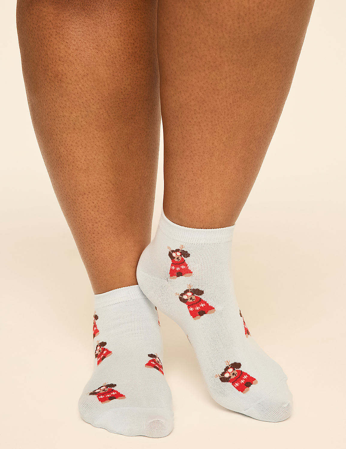 A person wears white socks featuring small red-dressed reindeer against a plain, light-colored background. Product Image 4