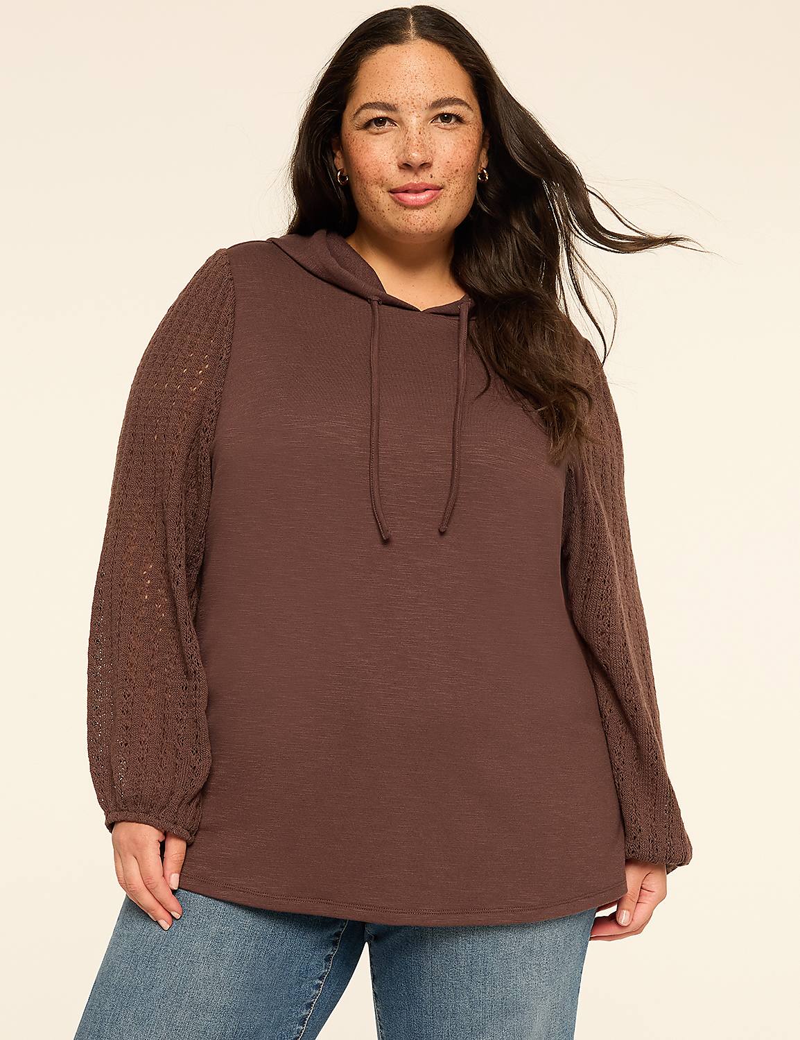 A smiling woman with blonde hair and a grey hoodie with sheer sleeves stands against a plain, light-colored background. Product Image 1