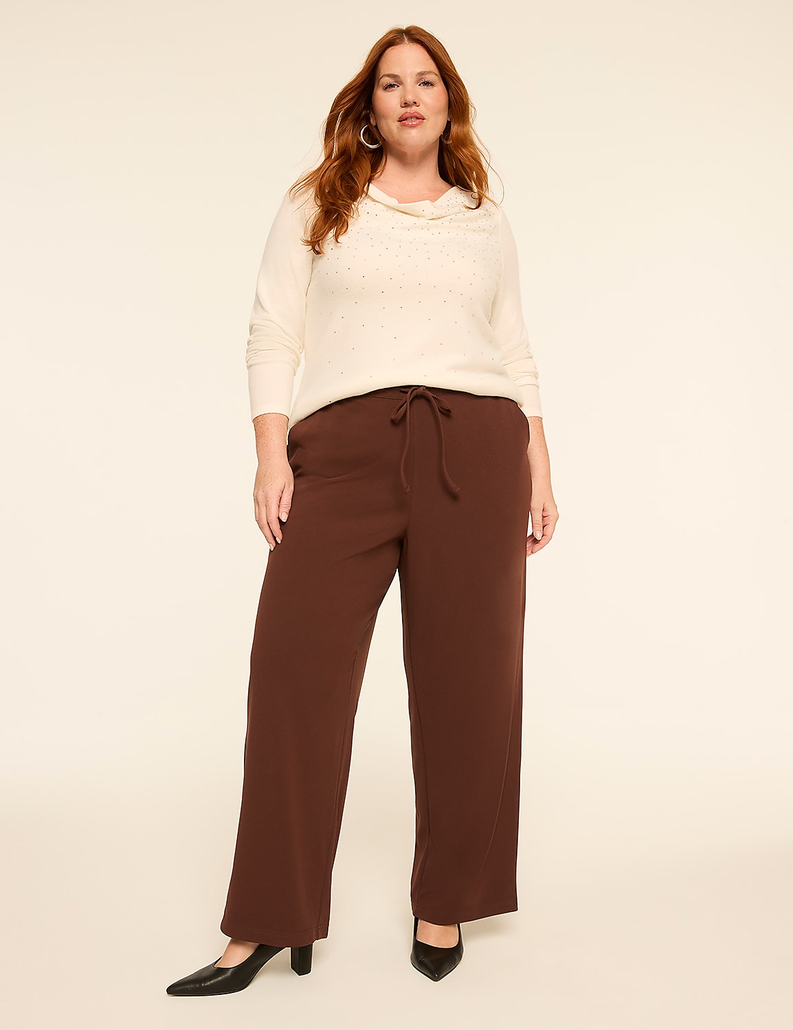A woman wearing a cream-colored sweater and brown wide-leg pants stands against a plain, light-colored background. Product Image 3