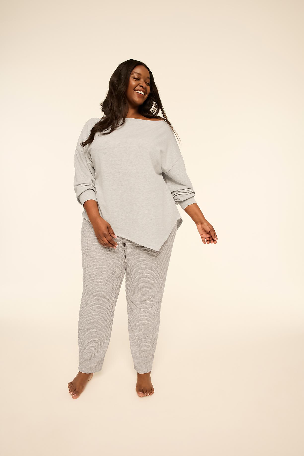 A smiling woman wearing a grey long-sleeved top and matching striped pants stands against a plain, light-colored background. Product Image 1