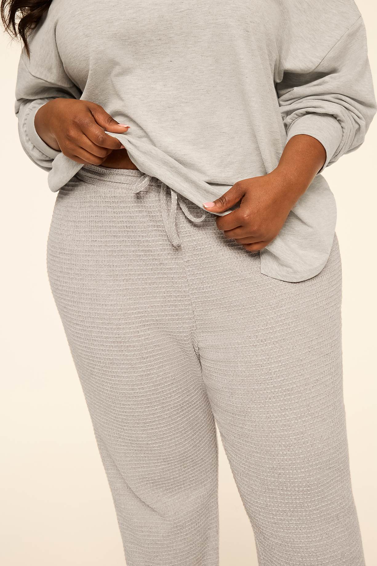 A person wears a light grey long-sleeved top and matching textured lounge pants against a plain, neutral background. Product Image 4