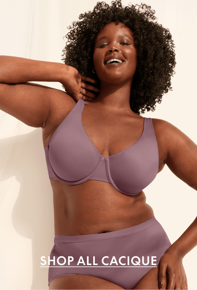 A woman in a pink bra and underwear stands in front of a draped pink curtain.